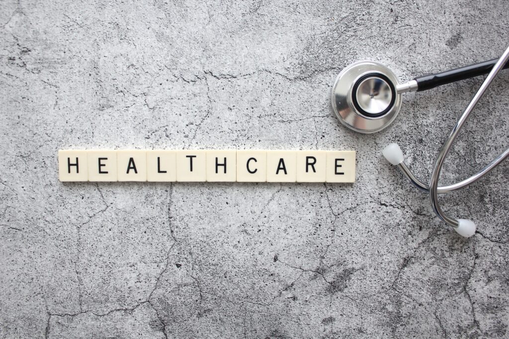 Healthcare spelled out in letter tiles with a doctor's stethoscope on a concrete background